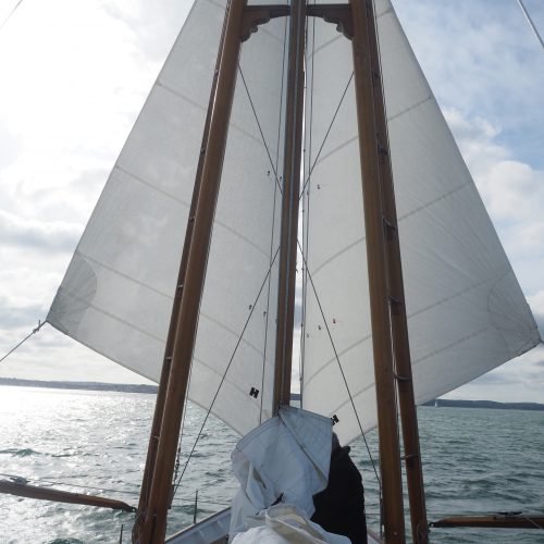Boleh heading downwind, sporting her signature rig of boomed-out headsails and with a hint of sunshine ahead.