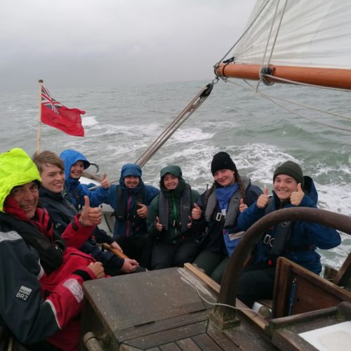 Crowded cockpit of Boleh under sail in grey weather