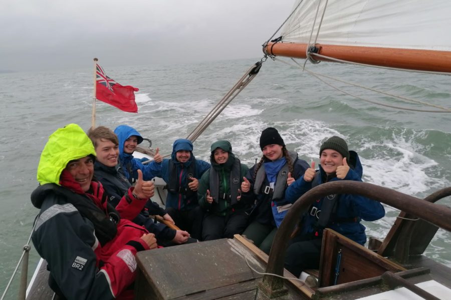 Crowded cockpit of Boleh under sail in grey weather
