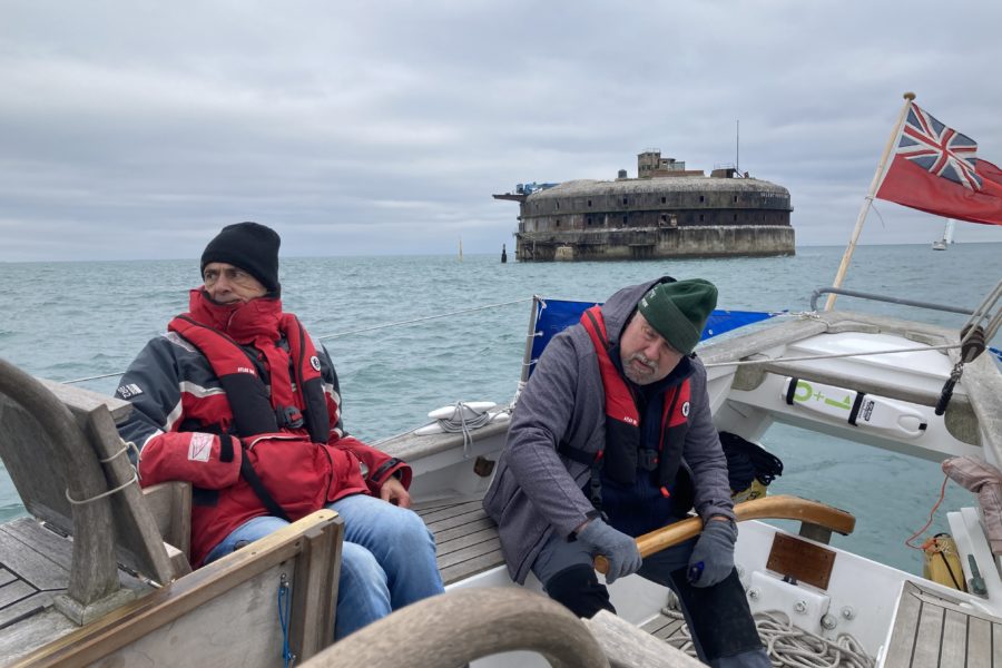 Two men on boat with old fort behind them